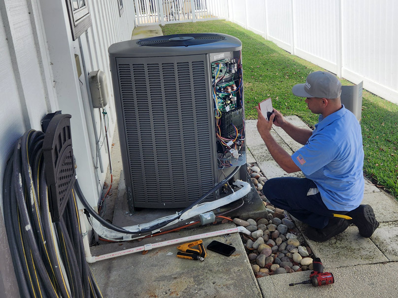 AC Maintenance Air Squad technician doing maintenance on an air conditioner with a tablet